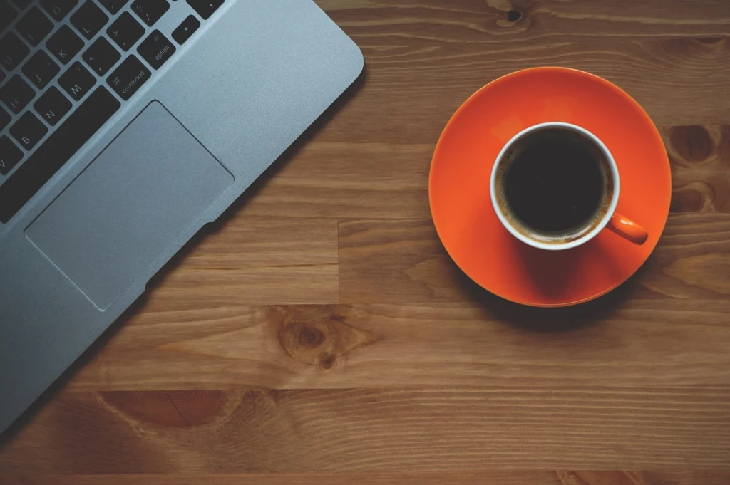 A desk with a laptop and coffee, workspace for SERP analysis